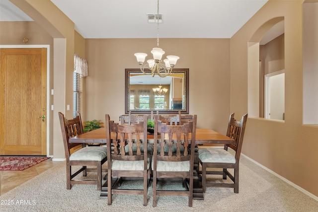 dining area with arched walkways, baseboards, a chandelier, and visible vents