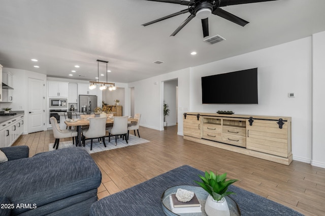 living room with recessed lighting, visible vents, light wood-type flooring, and baseboards