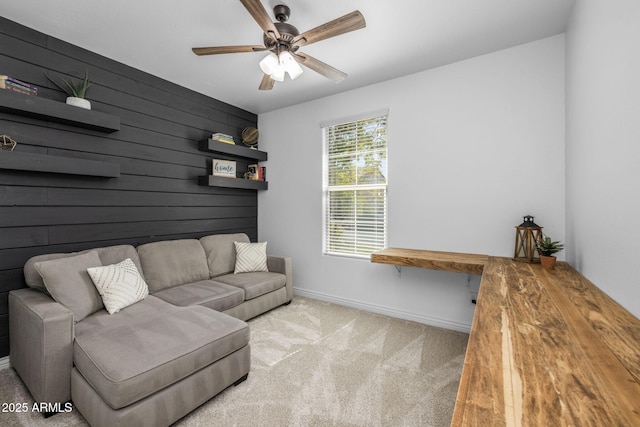 living area with ceiling fan, wood walls, baseboards, and carpet