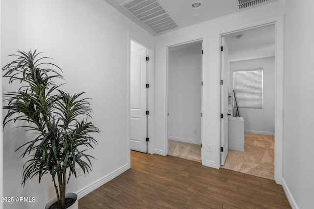 hall with visible vents, baseboards, and wood finished floors