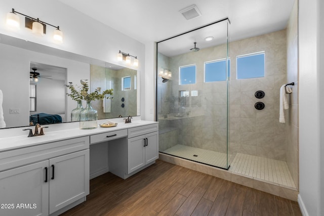 ensuite bathroom with a sink, connected bathroom, tiled shower, and wood finished floors