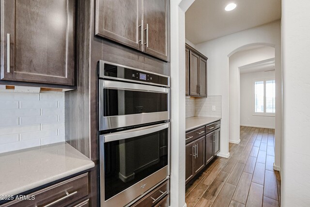 kitchen with decorative light fixtures, a center island with sink, wall chimney exhaust hood, dark wood-type flooring, and stainless steel appliances