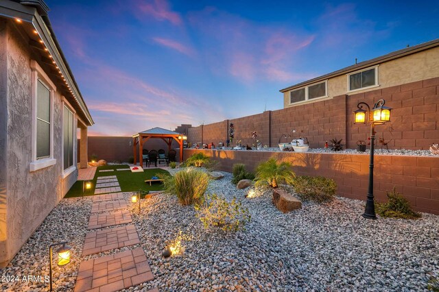 yard at dusk with a gazebo and a patio area