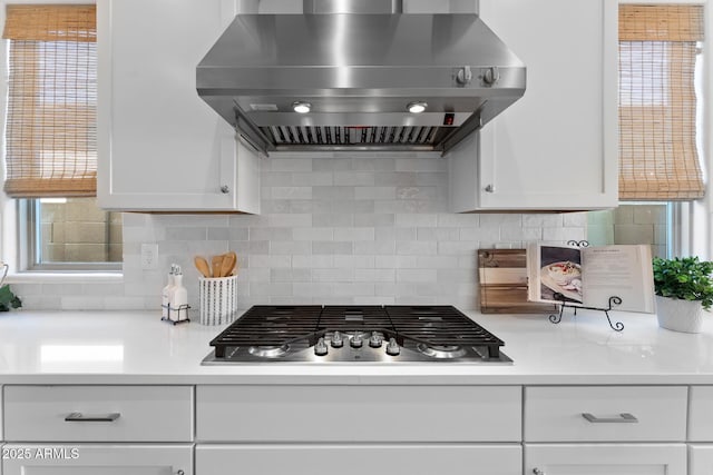 kitchen with extractor fan, backsplash, white cabinets, and stainless steel gas stovetop