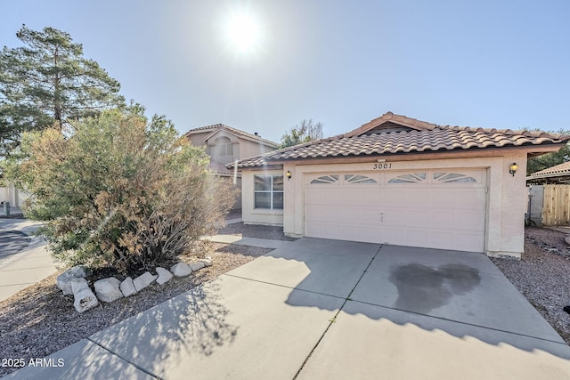 mediterranean / spanish home featuring a garage, a tiled roof, concrete driveway, and stucco siding