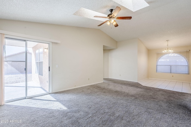 carpeted empty room featuring a wealth of natural light, vaulted ceiling with skylight, a textured ceiling, and ceiling fan with notable chandelier