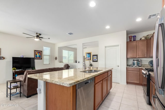 kitchen featuring ceiling fan, stainless steel appliances, light tile flooring, a kitchen island with sink, and sink