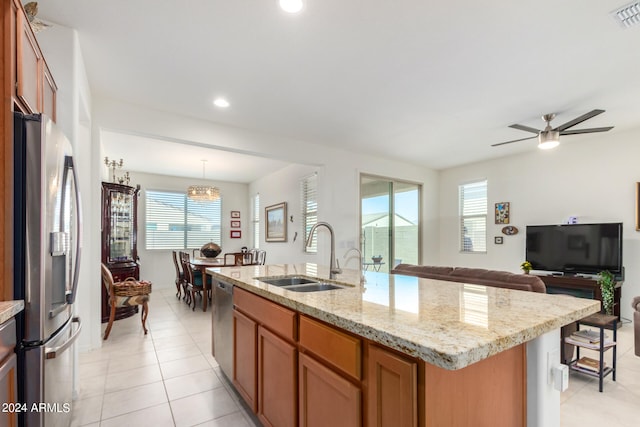 kitchen with appliances with stainless steel finishes, hanging light fixtures, ceiling fan, a kitchen island with sink, and sink