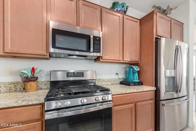 kitchen with light stone counters and appliances with stainless steel finishes