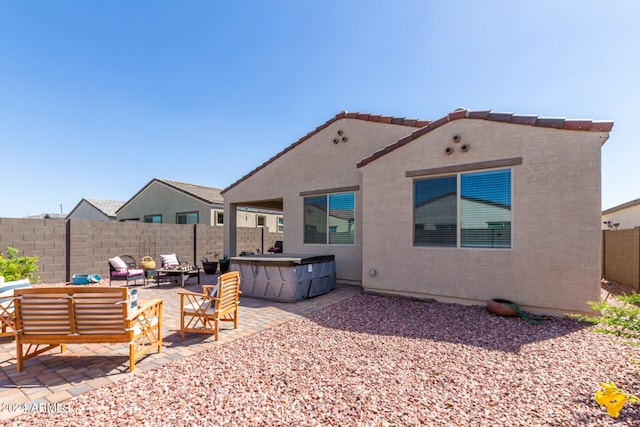 back of house with outdoor lounge area, a hot tub, and a patio