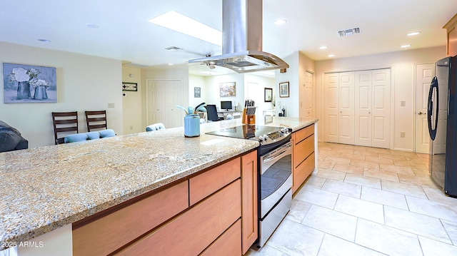 kitchen featuring freestanding refrigerator, stainless steel range with electric cooktop, visible vents, and island range hood