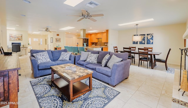 living area with a skylight, visible vents, light tile patterned flooring, and ceiling fan