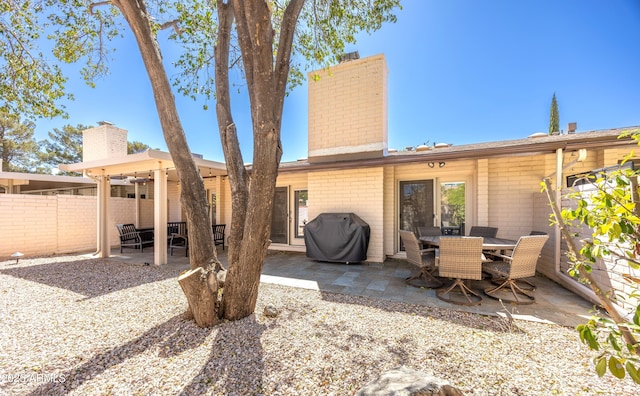 rear view of property with a chimney, a patio area, and fence