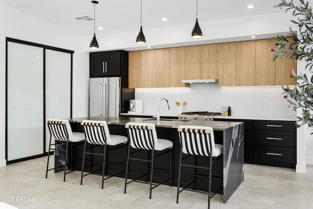 4002 N 33rd Pl, Phoenix, AZ 85018 - kitchen with high end fridge, under cabinet range hood, dark cabinetry, a kitchen breakfast bar, and a center island with sink