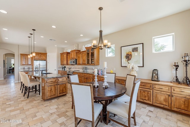 tiled dining area featuring a notable chandelier, sink, and a healthy amount of sunlight