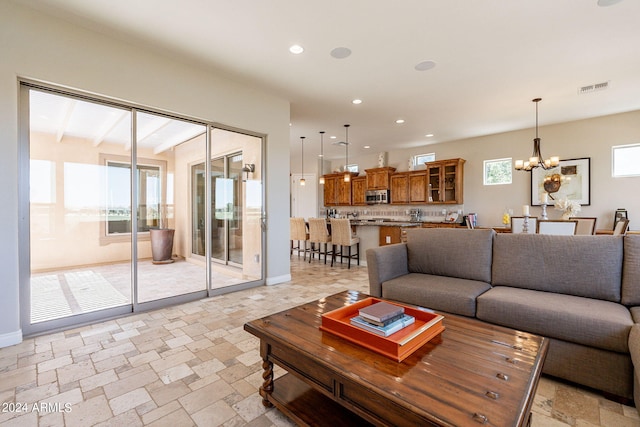 living room with beamed ceiling, light tile floors, and an inviting chandelier