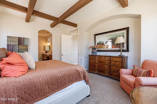 bedroom with connected bathroom, beam ceiling, and carpet floors