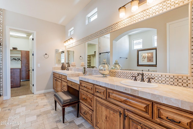 bathroom featuring a wealth of natural light, tile flooring, double sink vanity, and backsplash