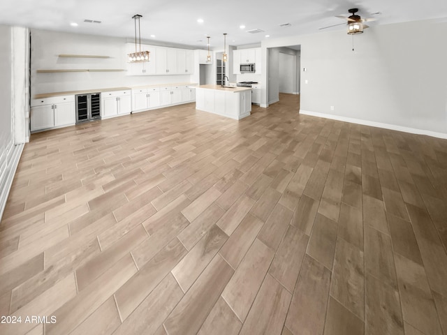 unfurnished living room with ceiling fan, sink, and beverage cooler