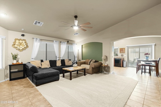 living room featuring ceiling fan, light tile patterned floors, and vaulted ceiling