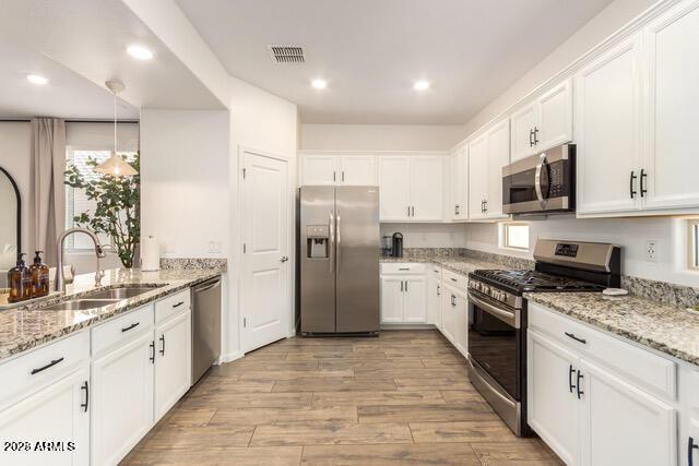 kitchen with visible vents, appliances with stainless steel finishes, white cabinetry, and a sink