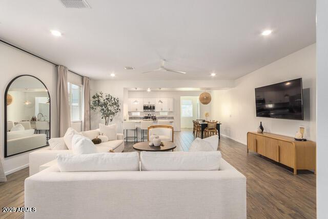 living area featuring a wealth of natural light, visible vents, and wood finished floors