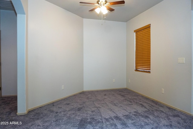 empty room with carpet, baseboards, ceiling fan, and arched walkways