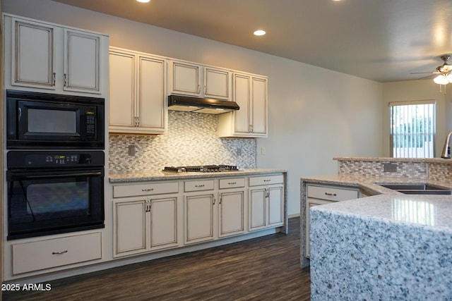 kitchen featuring decorative backsplash, a sink, light stone countertops, under cabinet range hood, and black appliances