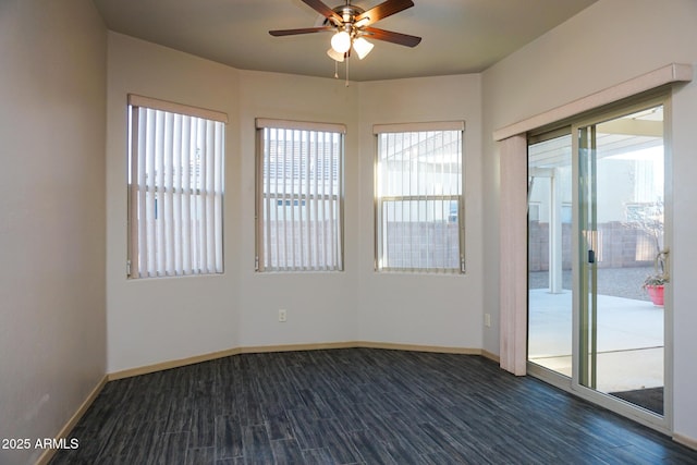 empty room with dark wood-style flooring, a ceiling fan, and baseboards