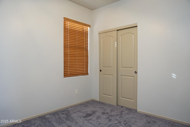 unfurnished bedroom with carpet floors, a closet, and baseboards