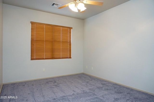 carpeted empty room with baseboards, visible vents, and a ceiling fan