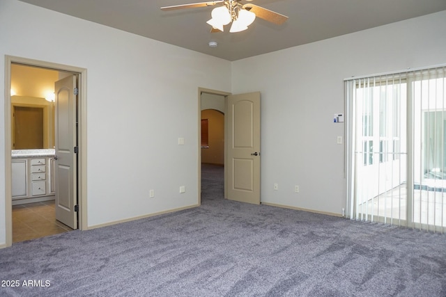 unfurnished bedroom with light carpet, access to exterior, arched walkways, and connected bathroom