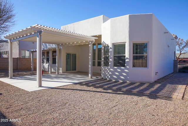 back of property with stucco siding, fence, a pergola, and a patio