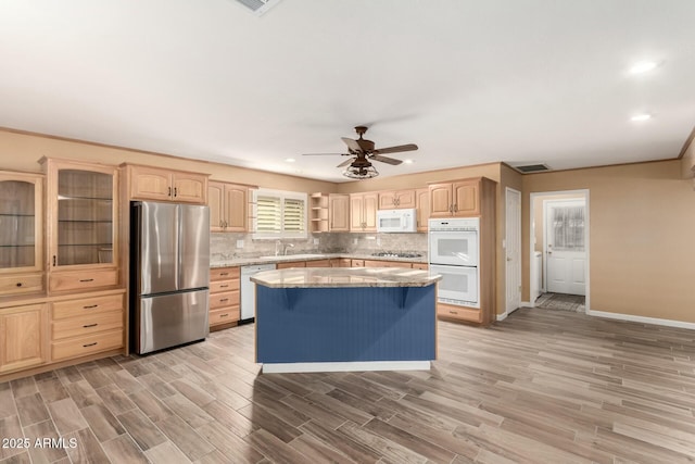 kitchen with decorative backsplash, light brown cabinetry, stainless steel appliances, a center island, and light hardwood / wood-style floors