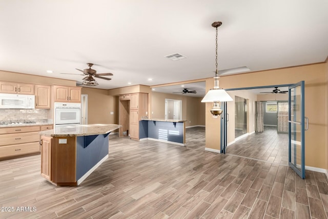 kitchen featuring backsplash, white appliances, pendant lighting, light brown cabinets, and a kitchen island