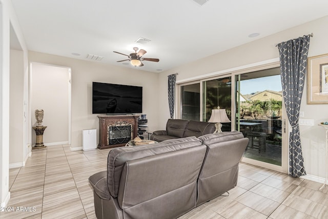 tiled living room featuring a fireplace and ceiling fan