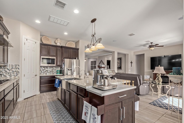 kitchen featuring decorative light fixtures, a kitchen island with sink, appliances with stainless steel finishes, and decorative backsplash