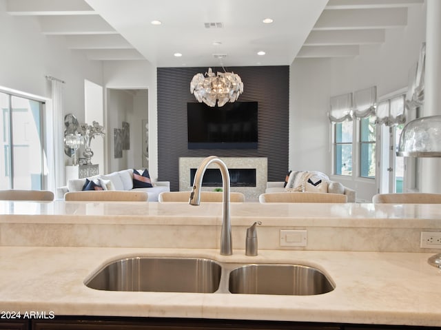 kitchen featuring beamed ceiling, sink, and a chandelier