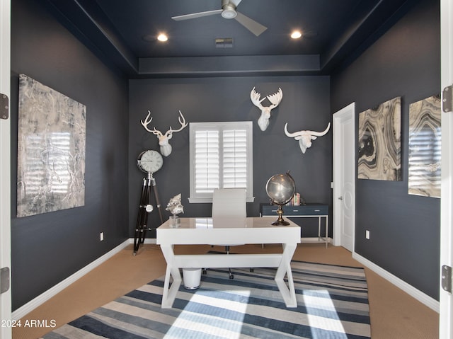 office area with carpet flooring, ceiling fan, and a tray ceiling