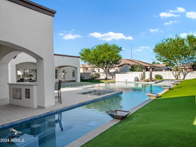 view of pool with a bar, a yard, a patio, and an in ground hot tub