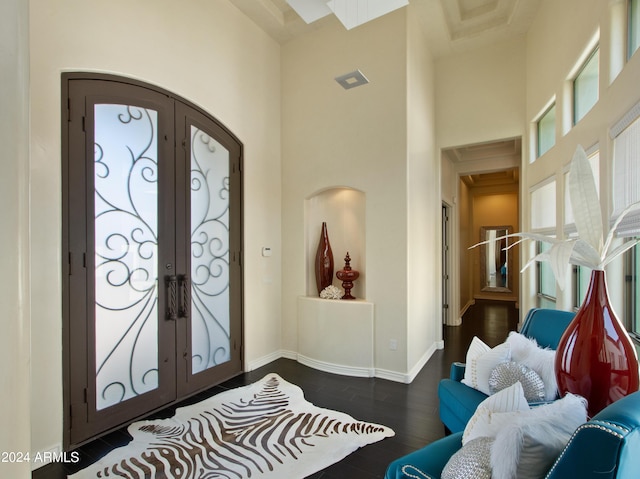 entryway featuring french doors, a towering ceiling, and dark wood-type flooring