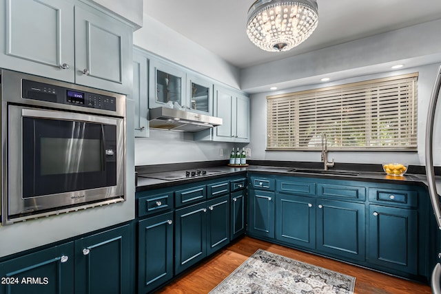 kitchen with sink, stainless steel oven, stovetop, blue cabinetry, and dark hardwood / wood-style floors