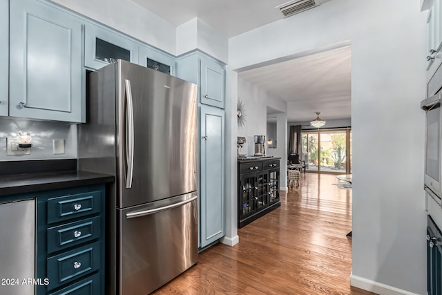 kitchen with hardwood / wood-style flooring, stainless steel refrigerator, and blue cabinets