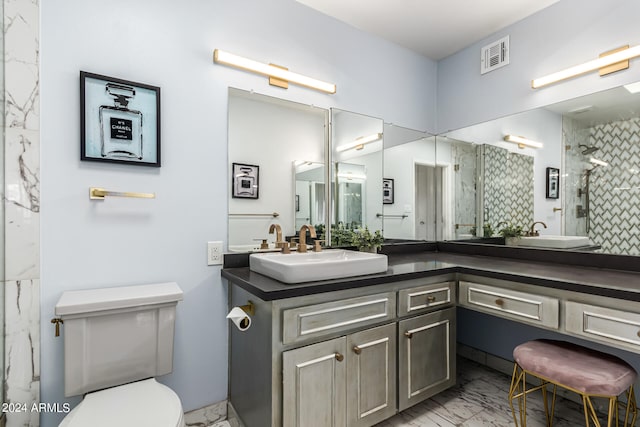 bathroom with vanity, toilet, and a tile shower