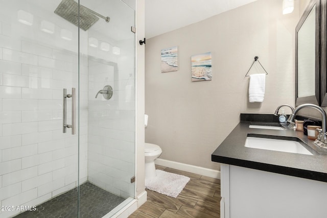 full bathroom featuring a stall shower, baseboards, toilet, wood finished floors, and vanity