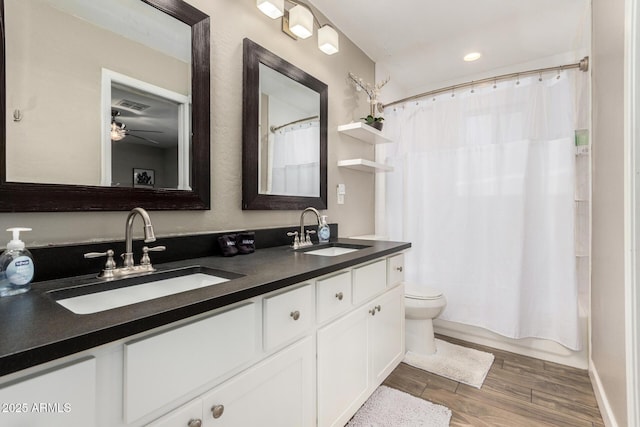 full bathroom featuring double vanity, wood finished floors, a sink, and visible vents