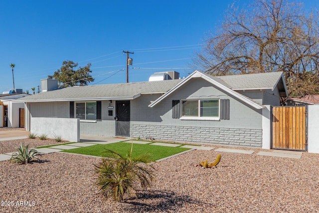 ranch-style home featuring roof with shingles, a gate, and brick siding