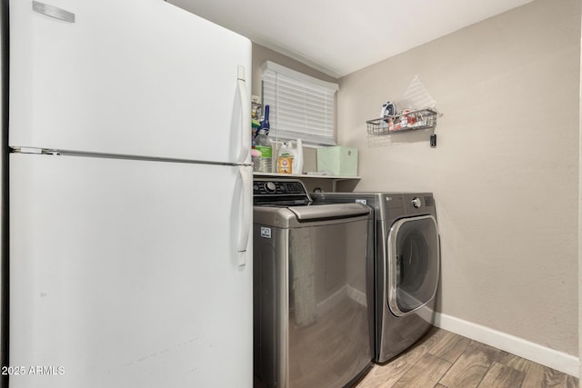 laundry area featuring laundry area, light wood-style flooring, baseboards, and separate washer and dryer