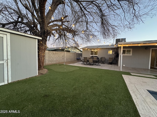 view of yard featuring a patio, central AC, fence, a shed, and an outdoor structure