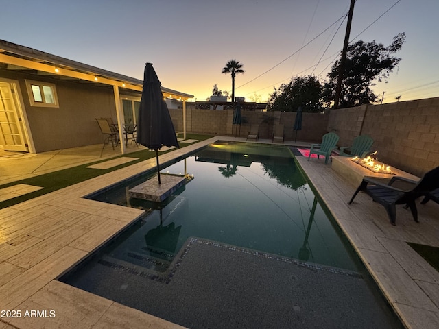 pool at dusk featuring a fenced in pool, a fenced backyard, and a patio